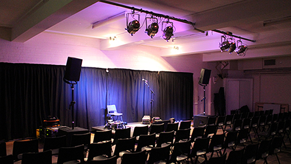 set-up for a gig in Trefusis - dark lighting with rows of chairs facing performance space