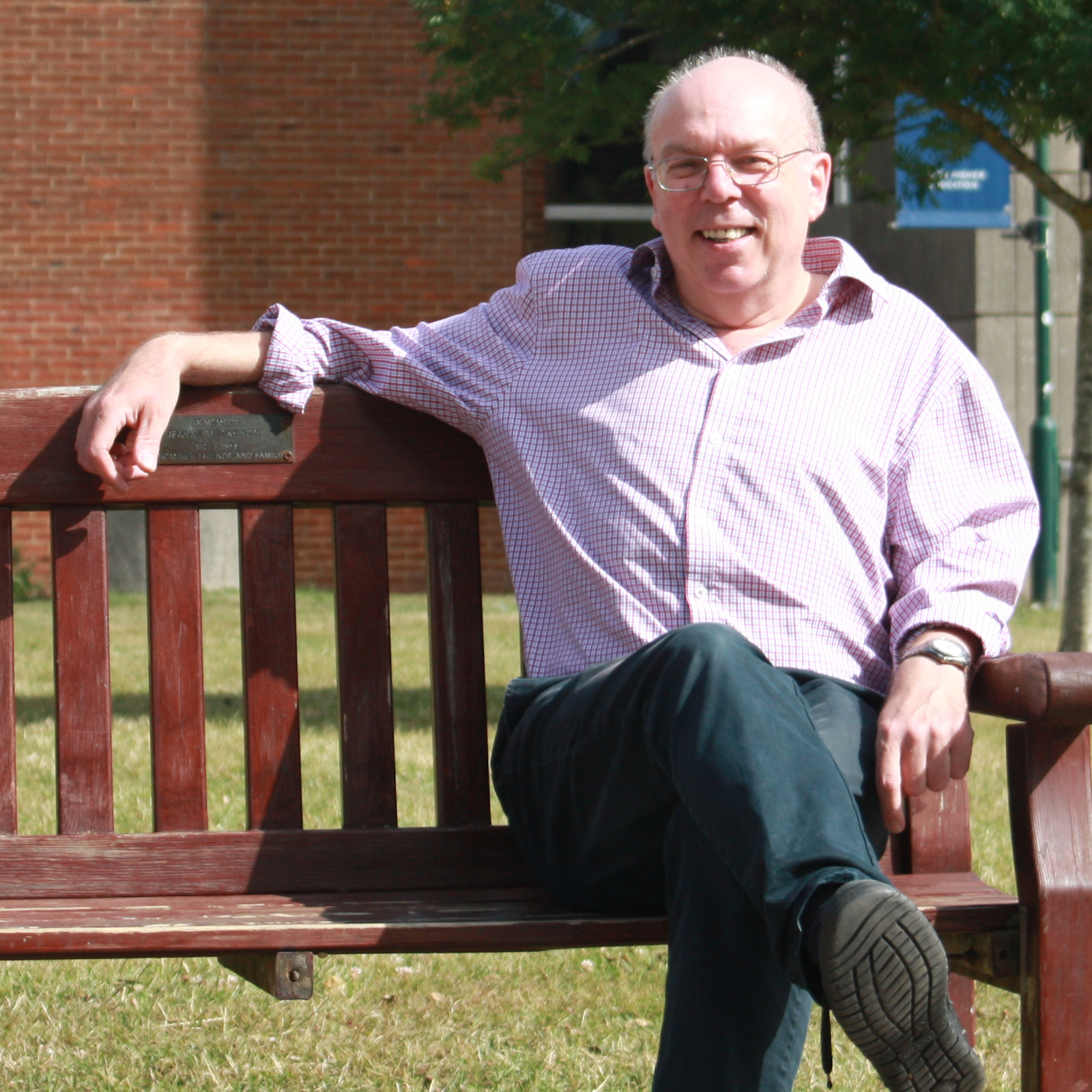 smiling man in relaxed pose on outside bench